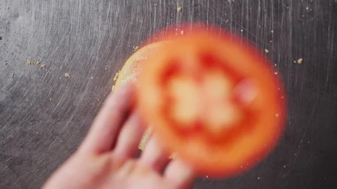 Woman throws tomato slice onto hamburger bun on metal table Video stock 124587285