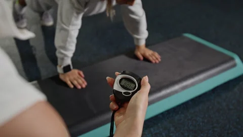 Woman Timing Boy Doing Plank Exercise on Step Platform in Gym Stock Footage 343382720