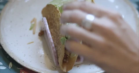 Woman topping taco with vegetables and shredded lettuce (shredduce) Stock Footage