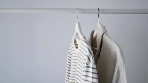 Woman touches light-colored striped vest hanging on white wooden hanger Stock Footage 340266539