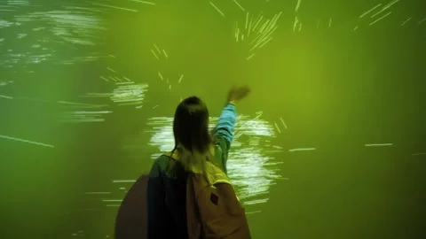 Woman touching immersive projection wall creating digital particle trail Stock Footage 339026324