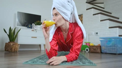 Woman with a towel on her head drinks juice while standing in a plank at home Stock Footage 143767341