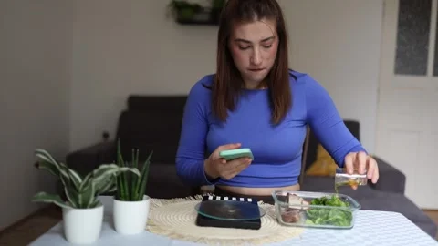 Woman tracks calories while adding olive oil to a healthy meal Stock Footage 339856577
