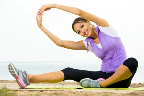 Woman training yoga poses sitting on beach Stock Photos