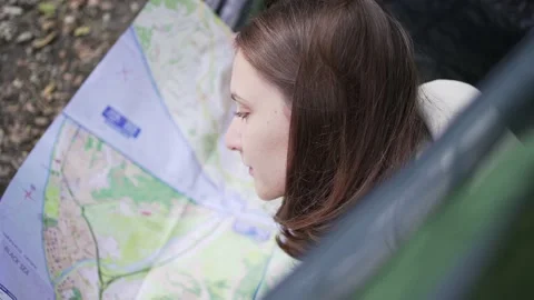 A woman traveler studies the map while lying in a tent. Opens a new direction Stock Footage 164528704