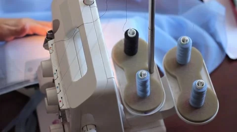 Woman treated tissue using overlock. Skeins of thread. Women's hands Stock Footage 67229575