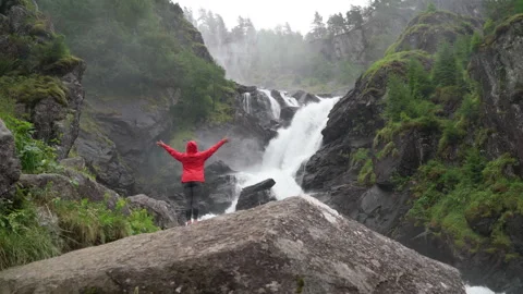 Woman trekker dressed bright red waterproof jacket with enjoying Låtefossen Wate Video stock 284745053