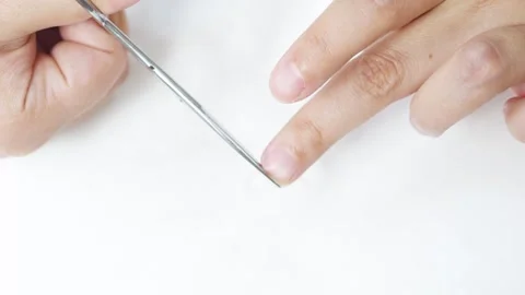 Woman trimming fingernails using compact scissors against pristine white Stock Footage 308522372