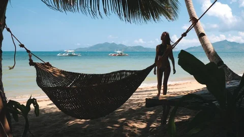 Woman on tropical beach rope hammock on palm tree Stock Footage