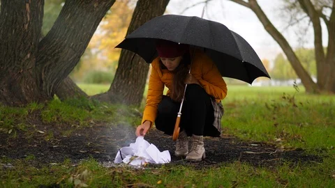 Woman try to make fire under rain in windy autumn park Stock Footage 96175773