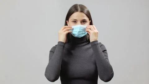 Woman trying to fit too large face mask to her face by twisting ear rubbers Stock Footage 171631253