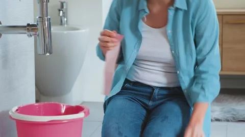 Woman trying to fix a leaking pipe with adhesive tape Stock Footage 297857912