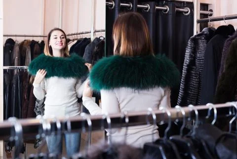 Woman trying on fur neckpiece in women’s cloths store Stock Photos