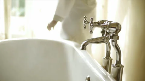 Woman turning off hot water bathtub faucet in the bathroom Stock Footage