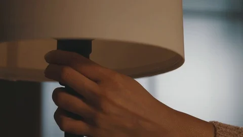 Woman turning on a table lamp at home Stock Footage