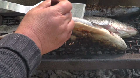 Woman turning trout on the grill, frying freshwater fish, delicious meal, food Stock Footage
