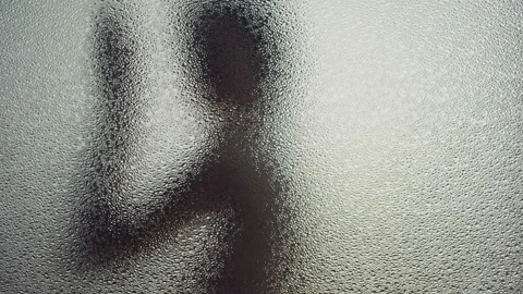 Woman turning while dancing behind a frosted glass window Video stock 259706162