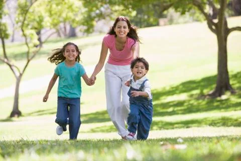 Woman with two young children running outdoors smiling Stock Photos
