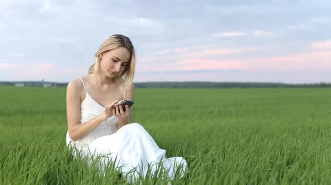 Woman types message lying down in the park: smartphone: mobile phone, outdoor Stock Footage 64012063