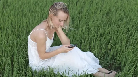 Woman types message lying down in the park: smartphone: mobile phone, outdoor Stock Footage 64012160