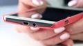 Woman types sms on smartphone. Close up of woman hands with red smartphone HD Footage
