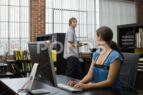 A woman typing and looking at a colleague Stock Photos