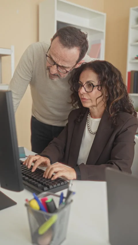 Woman typing on computer, middle aged man leaning over and placing hand on .. Stock Footage 339239411