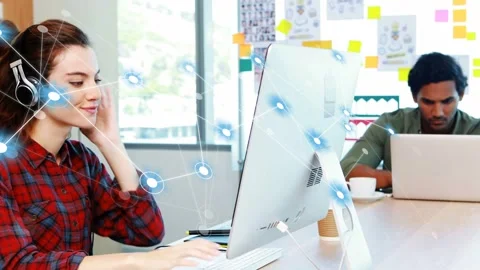 Woman typing in creative office causing network nodes to expand across monitor Stock Footage 334322004