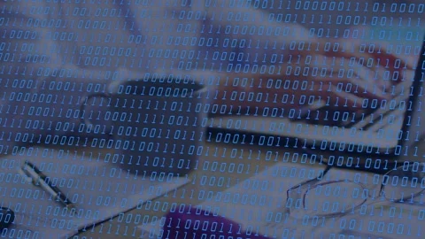 Woman typing off-frame on laptop, binary overlay animating over laptop and desk Stock Footage 335652105