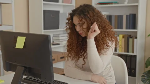 Woman typing on keyboard with hands on keys at a desk, looking down at moni.. Stock Footage 339257543