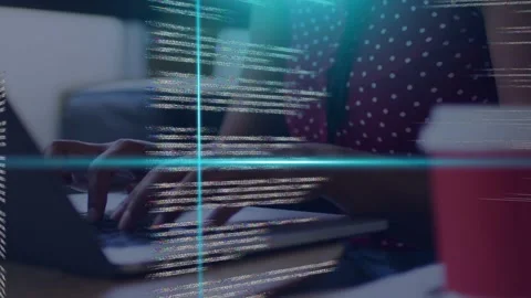 Woman typing laptop keys causing cyan code grid, camera pulling back revealing Stockbeeldmateriaal 335761644