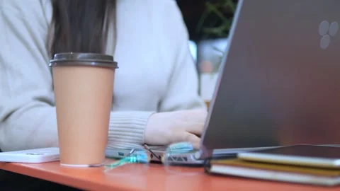 Woman is typing on a laptop while holding a coffee cup Stock Footage 307005580