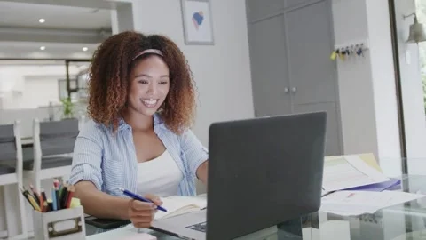 Woman typing on laptop while taking notes at glass table, causing teal swirl Stockbeeldmateriaal 333894458