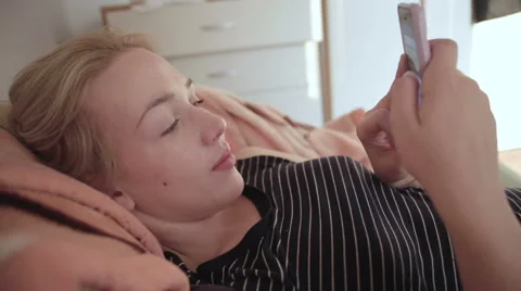 Woman typing on the phone in a lying position 스톡 동영상 59188519