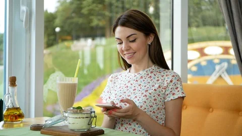 Woman typing write message on smart phone in a modern cafe. Cropped image of 스톡 동영상 99398931