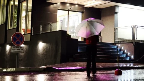 Woman with an umbrella walks on a night city on rainy weather Stock Footage