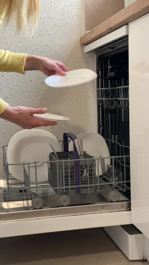 Woman unloading clean white plates from the dishwasher basket in a modern k.. Stock Footage 331884322