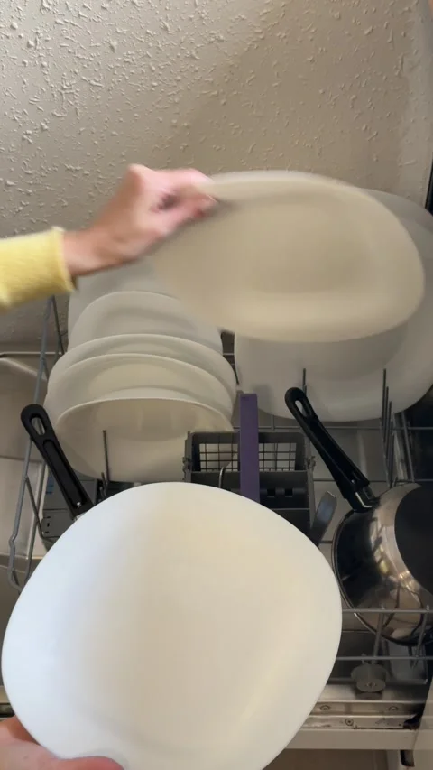 Woman unloading clean white plates and kitchenware from a modern dishwasher.. Stock Footage 331884464