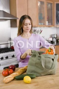 Woman Unloading Groceries from Cloth Bag on Kitchen Counter Stock Photos