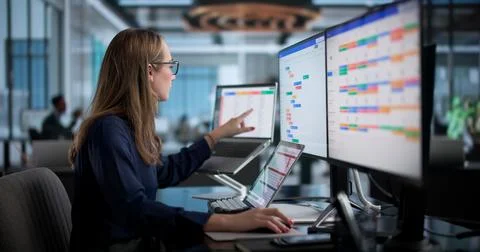 Woman Updates Project Task Board Using Laptop While Managing Office Schedule. Stock Photos