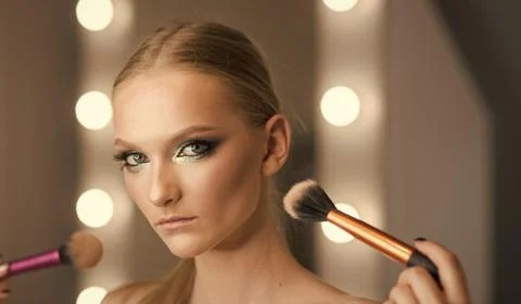 Woman use brushes for makeup, visage. Woman with young face skin in beauty salon Stock Photos