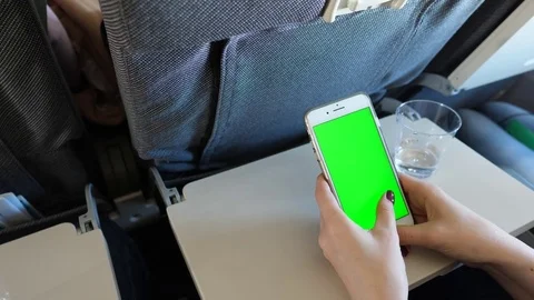 Woman use large smartphone during flight, review images on screen, green chroma Stock Footage