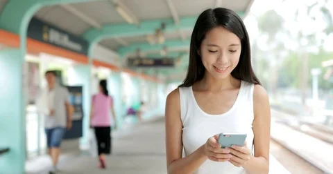 Woman use of mobile phone and walking in the light rail platform Stock Footage