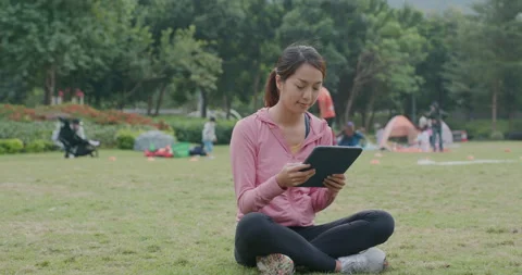 Woman use of tablet computer and sit on the green lawn Video stock 146912152