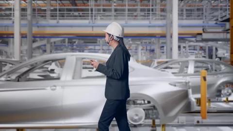 Woman Use Tablet While Walking and Looking Around In Car Factory Stock Footage 331631319