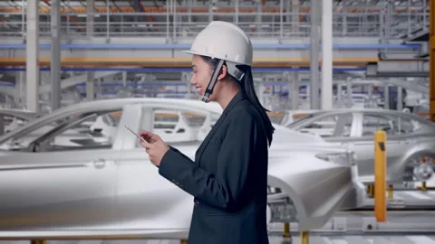 Woman Use Tablet While Walking and Looking Around In Car Factory Stock Footage 331631539
