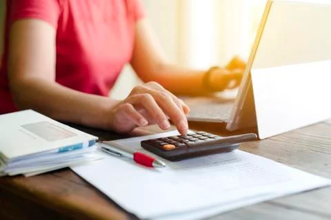 Woman uses a calculator while doing her finances - Recession - Bills - Job Stock Photos