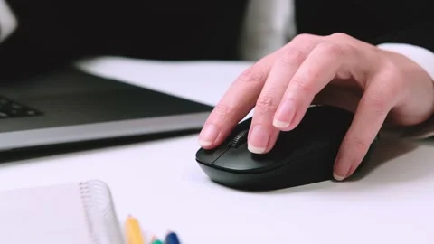 A woman uses a computer mouse while working on a laptop at a table Stock Footage 229659077