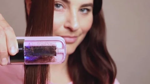 Woman  uses a machine to cut the split ends of her hair. Stock Footage 313131168