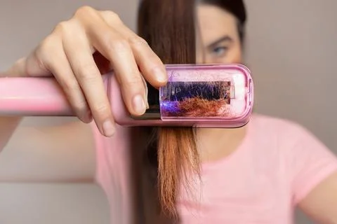 A woman uses a machine to cut the split ends of her hair. Close up photo. 스톡 사진